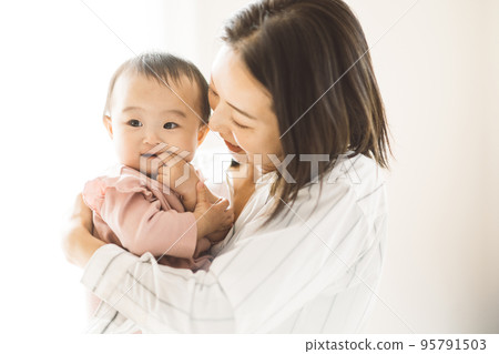smiling mom holding a baby 95791503
