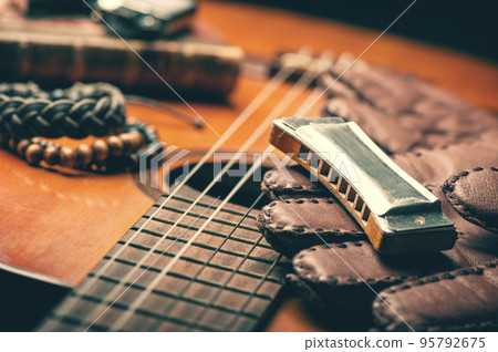 vintage harmonica on acoustic guitar 95792675