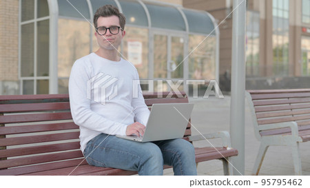 Rejecting Young Man in Denial While using Laptop Sitting Outdoor on Bench 95795462