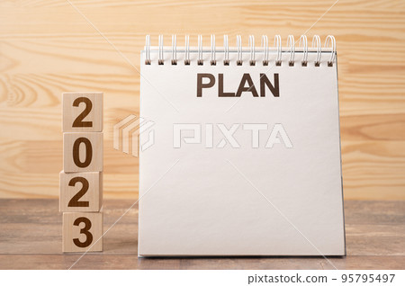 Mockup 2023 notepad with PLAN text. Text 2023 on wooden cubes. space for your text on notepad, New Year. startup concept. wooden background. Concept of new year planning. Mockup 2023 notepad with PLAN text. Text 2023 on wooden cubes. space for your text on notepad, New Year. startup concept. wooden background. Concept of new year planning. 95795497