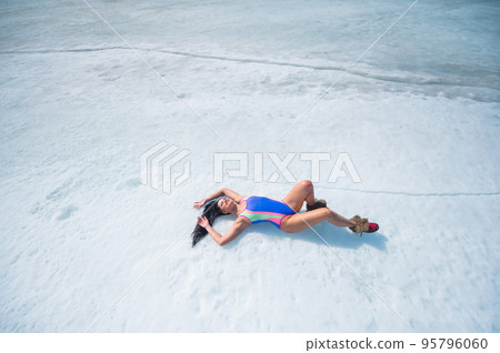 Caucasian woman in a swimsuit sunbathes on the snow in winter. 95796060