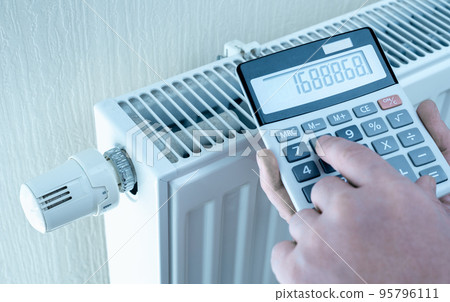 concept of expensive heating costs. hands with calculator consider cost of heating. saving energy in times of crisis caused by high cost of energy 95796111