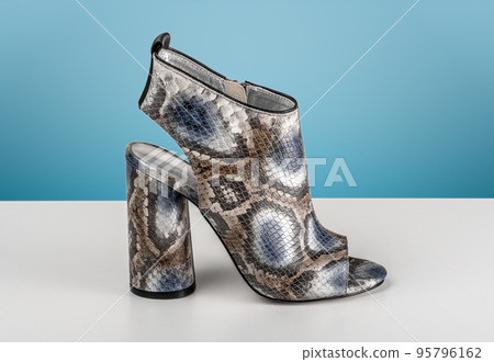 Women snake leather skin shoes with high heels. fashionable python leather sandals. artificial python snake skin. blue background Women snake leather skin shoes with high heels. fashionable python leather sandals. artificial python snake skin. blue background 95796162