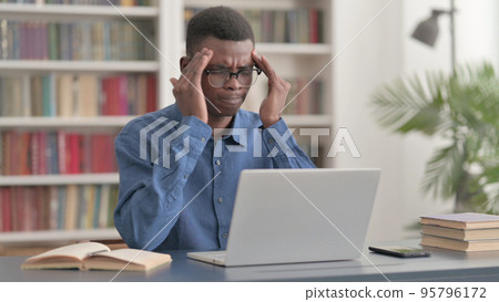 Young African Man having Headache while Working on Laptop 95796172