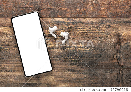 White wireless bluetooth earphones or headphones and smartphone over wooden rustic background. Audio technology apps, music podcasts books. Copy space. White wireless bluetooth earphones or headphones and smartphone over wooden rustic background. Audio technology apps, music podcasts books. Copy space. 95796918