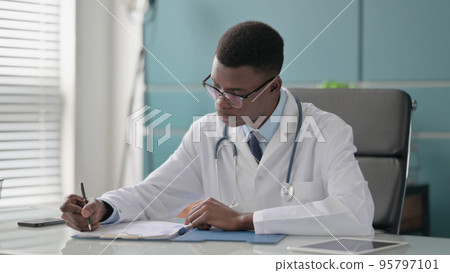Young African Doctor Writing on Paper in Clinic Young African Doctor Writing on Paper in Clinic 95797101