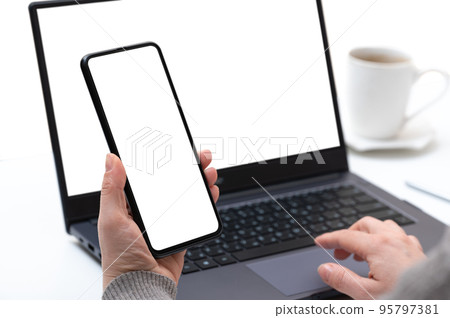 Mockup device. businesswoman using smartphone and notebook. female hands typing on laptop keyboard with blank white screen, cell phone and laptop use at same time 95797381