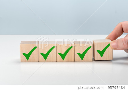 Checklist concept, check mark on wooden blocks on with copy space. Hand holding wooden blocks with check marks. Concept of questionary, checklist, to do list, planning or business plans 95797484