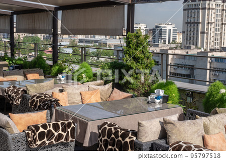 rooftop bar, overlooking a magnificent cityscape blue sky. cafe on the roof of the building. Table setting on roof top restaurant with megapolis view rooftop bar, overlooking a magnificent cityscape blue sky. cafe on the roof of the building. Table setting on roof top restaurant with megapolis view 95797518
