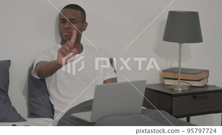Rejecting African Man with Laptop Shaking Head as No Sign in Bed Rejecting African Man with Laptop Shaking Head as No Sign in Bed 95797724