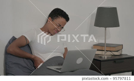 African Woman having Back Pain while using Laptop in Bed African Woman having Back Pain while using Laptop in Bed 95797811