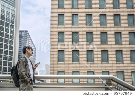 Young businessman operating a smartphone in office casual Young businessman operating a smartphone in office casual 95797949