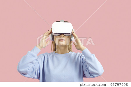 Woman isolated on color background experiencing virtual reality in innovative VR goggles 95797998