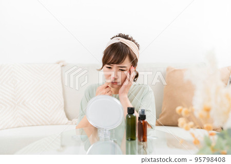 Women who are worried about their skin looking in the mirror (nose, pores) Women who are worried about their skin looking in the mirror (nose, pores) 95798408
