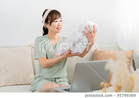 A woman comforting a baby while teleworking A woman comforting a baby while teleworking 95799369