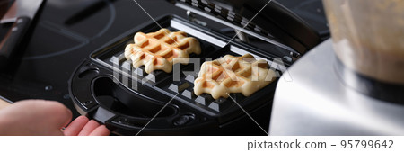 Cooking waffles in waffle iron at home closeup 95799642