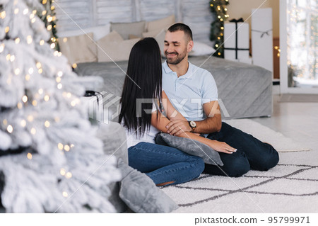 Portrait of man and woman on holiday. Handsome man with his beautiful wife in decorated room. Christmas mood. Background of fairy lights 95799971