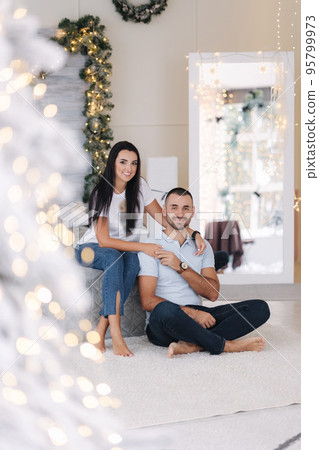 Portrait of man and woman on holiday. Handsome man with his beautiful wife in decorated room. Christmas mood. Background of fairy lights 95799973
