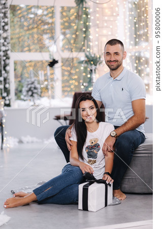Portrait of man and woman on holiday. Handsome man with his beautiful wife in decorated room. Christmas mood. Fairytail Portrait of man and woman on holiday. Handsome man with his beautiful wife in decorated room. Christmas mood. Fairytail 95800006