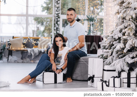 Portrait of man and woman on holiday. Handsome man with his beautiful wife in decorated room. Christmas mood. Fairytail Portrait of man and woman on holiday. Handsome man with his beautiful wife in decorated room. Christmas mood. Fairytail 95800007