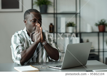 Young troubled African American man keeping hands by his face 95802104
