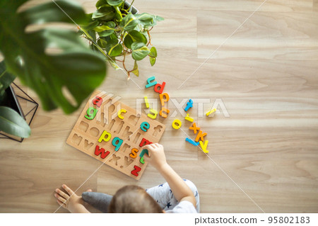 Male kid playing with wooden eco friendly alphabet letters board on table top view intellectual game Male kid playing with wooden eco friendly alphabet letters board on table top view intellectual game 95802183