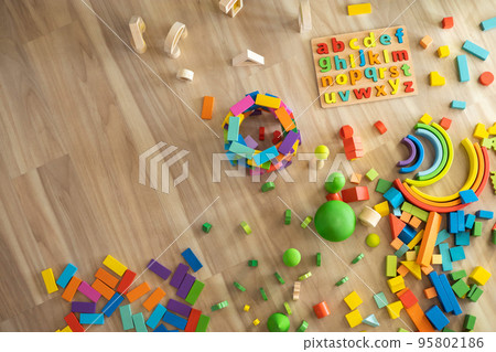 Alphabet wooden board with colored font letters. Colored wooden blocks for building and toy trees and plants. Top view. Alphabet wooden board with colored font letters. Colored wooden blocks for building and toy trees and plants. Top view. 95802186