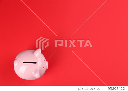 Pink piggy bank on red background, top view. Space for text Pink piggy bank on red background, top view. Space for text 95802422