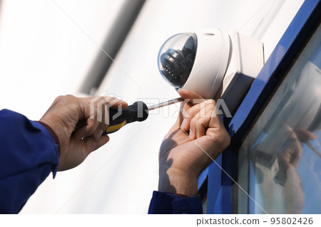 Technician installing CCTV camera on wall outdoors, closeup Technician installing CCTV camera on wall outdoors, closeup 95802426