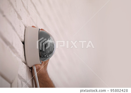 Technician installing CCTV camera on wall, closeup. Space for text Technician installing CCTV camera on wall, closeup. Space for text 95802428