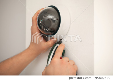 Technician installing CCTV camera on wall, closeup Technician installing CCTV camera on wall, closeup 95802429