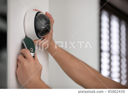 Technician installing CCTV camera on wall indoors, closeup Technician installing CCTV camera on wall indoors, closeup 95802430
