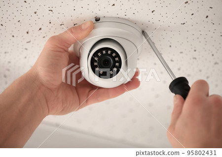 Technician installing CCTV camera on ceiling indoors, closeup 95802431