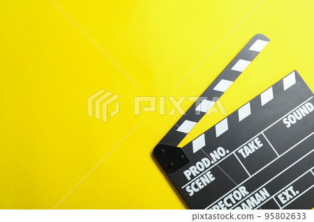 Clapper board on yellow background, top view with space for text. Cinema production 95802633