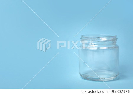 Open empty glass jar on light blue background, space for text Open empty glass jar on light blue background, space for text 95802976