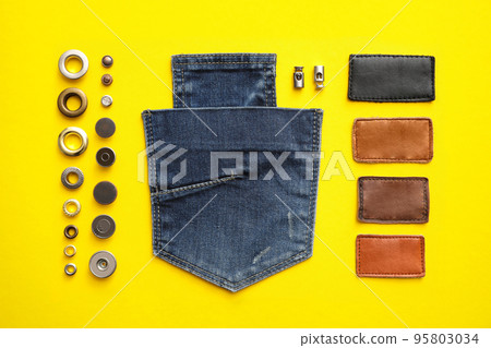 Flat lay composition with garment accessories and cutting details for jeans on yellow background Flat lay composition with garment accessories and cutting details for jeans on yellow background 95803034