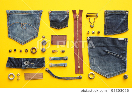 Flat lay composition with garment accessories and cutting details for jeans on yellow background Flat lay composition with garment accessories and cutting details for jeans on yellow background 95803036