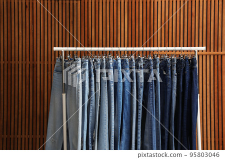Rack with different jeans on wooden background Rack with different jeans on wooden background 95803046