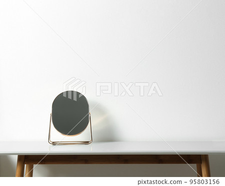 Small mirror on table near white wall. Space for text 95803156