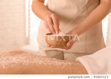 Young woman having body scrubbing procedure with sea salt in spa salon, closeup 95803323