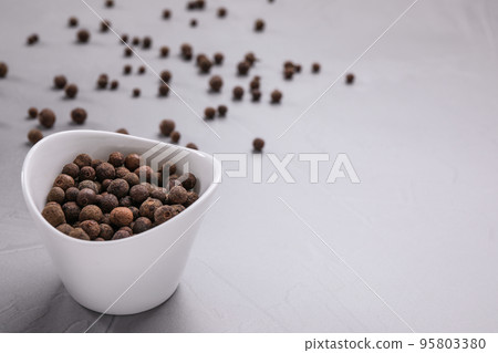 Black peppercorns in bowl on grey table. Space for text Black peppercorns in bowl on grey table. Space for text 95803380