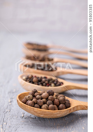 Spoons with peppercorns on grey wooden table, closeup Spoons with peppercorns on grey wooden table, closeup 95803385