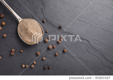 Ground black pepper and corns on black table, flat lay. Space for text Ground black pepper and corns on black table, flat lay. Space for text 95803387