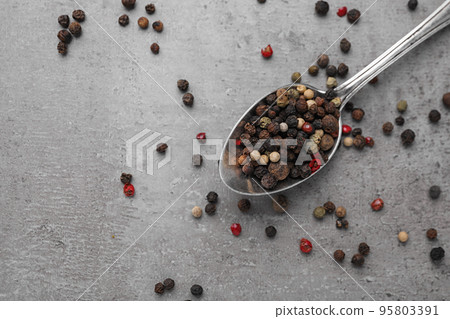 Spoon with mixed peppercorns on grey table, flat lay Spoon with mixed peppercorns on grey table, flat lay 95803391
