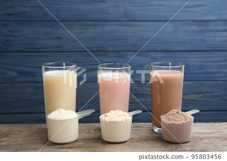 Protein shakes and powder on wooden table 95803456