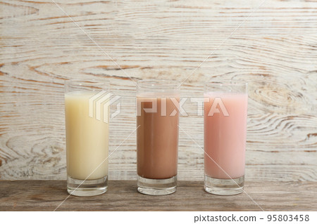 Different protein shakes in glasses on wooden table 95803458