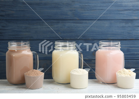 Protein shakes and powder on white wooden table 95803459