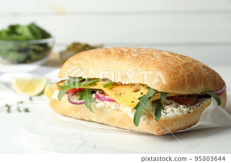 Delicious sandwich with fresh vegetables and cheese on white table 95803644