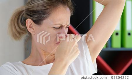 Young woman sniffing armpits and covering nose 95804252
