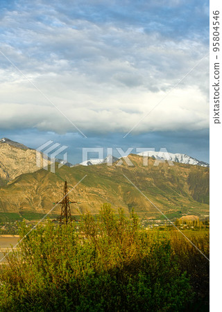 A vertical shot of mountains against the background of the cloudy sky. Central Asia A vertical shot of mountains against the background of the cloudy sky. Central Asia 95804546
